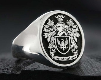 May include: A silver signet ring with a black oval top featuring a coat of arms with a bird and the text "Constantino".