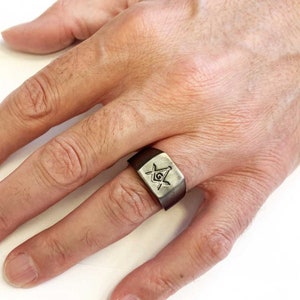May include: A brown leather ring with a silver Masonic symbol engraved on the top.