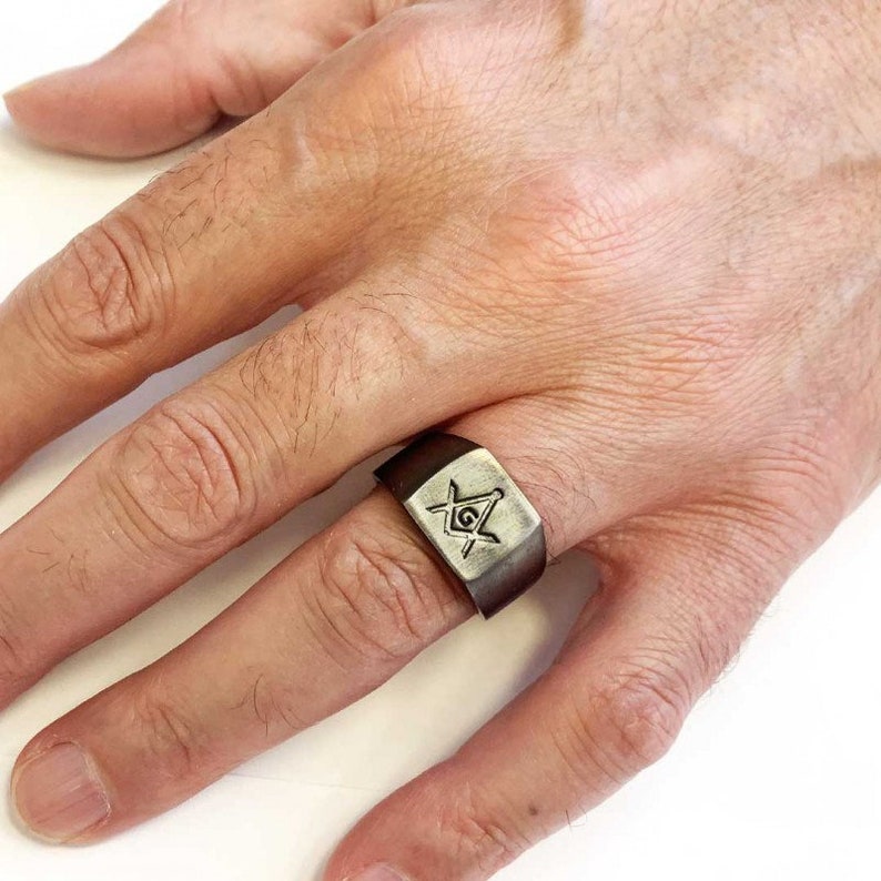 May include: A brown leather ring with a silver Masonic symbol engraved on the top.