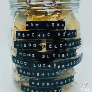 以下が含まれることがあります： 乾燥した月桂樹の葉で満たされたガラス瓶。瓶のラベルには、「月桂樹の葉」、「サイキックパワー」、「知恵の浄化」、「家の祝福」、「幸運」、「保護」、「追放」、「繁栄」、「豊穣」と書いてあります。