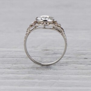 May include: A silver engagement ring with a large, round, clear center stone and smaller stones on the band. The ring has a delicate, intricate design.