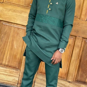 May include: A dark green two-piece suit with a long-sleeved top and matching pants. The top features gold-colored buttons and a decorative design. The suit is made of a textured fabric.
