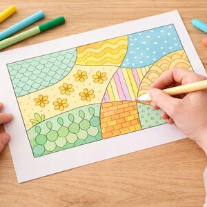 May include: A hand coloring a patterned illustration with a pink marker. The illustration features various geometric shapes and floral designs in yellow, green, blue, and orange. Several colored markers are scattered around the artwork on a wooden surface.