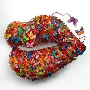May include: A red wire sculpture in the shape of a pair of lips, with hundreds of colorful butterflies attached to the wire.