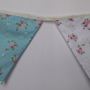 May include: A blue and white bunting with a floral pattern. The bunting is made of fabric and has a white ribbon running through it.