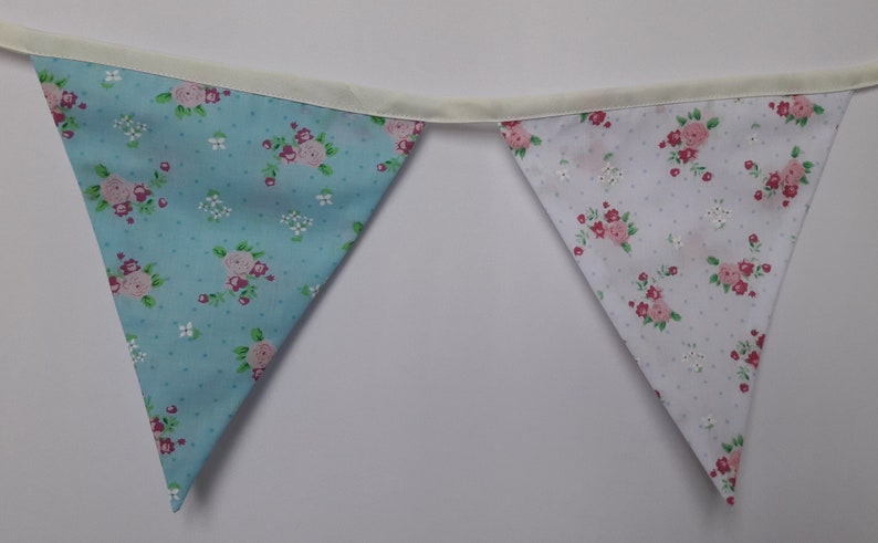 May include: A blue and white bunting with a floral pattern. The bunting is made of fabric and has a white ribbon running through it.