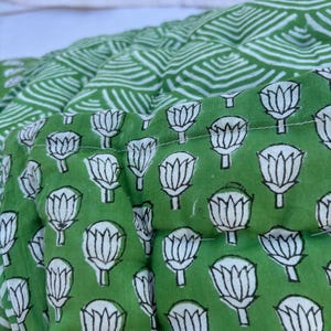 May include: Green fabric with a white floral pattern. The fabric is quilted and has a geometric pattern on the back.