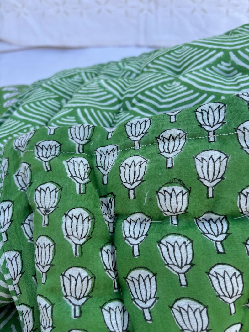 May include: Green fabric with a white floral pattern. The fabric is quilted and has a geometric pattern on the back.