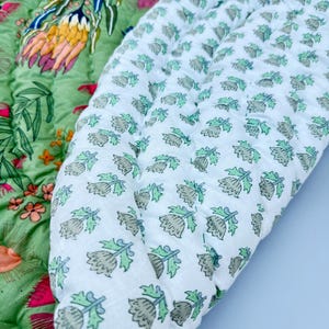 May include: A green and white quilted fabric with a floral pattern. The fabric is folded in half, showing both sides of the pattern.