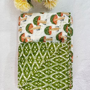 May include: A green and white reversible quilt with a mushroom print on one side and a geometric pattern on the other side.