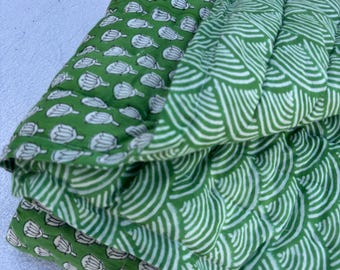 May include: A green cotton quilt with a floral pattern on one side and a wave pattern on the other side.