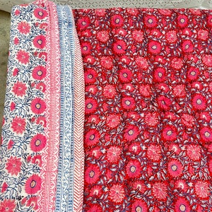 May include: A red and white floral patterned quilt with a white border. The quilt is made of cotton and has a hand-stitched look.