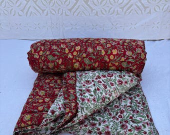May include: A red and white floral patterned quilt with a quilted design. The quilt is folded in half and rolled up.