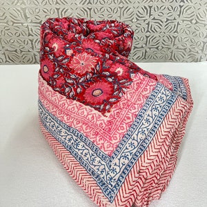 May include: A pink and blue cotton quilt with a floral pattern. The quilt is folded in a triangular shape.