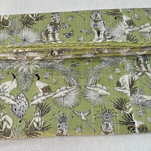 May include: A green kantha quilt with a repeating pattern of tigers, monkeys, birds, and butterflies. The quilt is made of cotton and has a hand-stitched design.