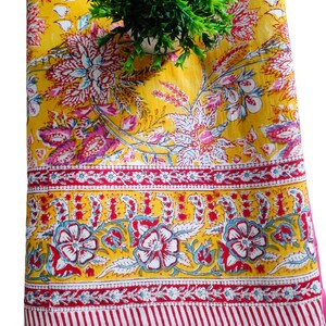 May include: A yellow cotton quilt with a pink floral pattern. The quilt has a pink border and a white and red striped border.