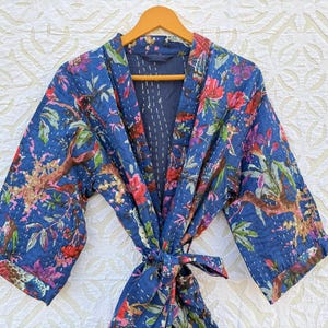 Könnte beinhalten: Eine blaue Baumwollrobe mit Blumendruck und einem Bindegürtel. Die Robe hat einen traditionellen japanischen Kimono-Stil.