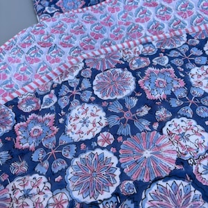 May include: A blue and pink floral patterned fabric with a white stripe border. The fabric is made of cotton and is perfect for quilting, sewing, or crafting.