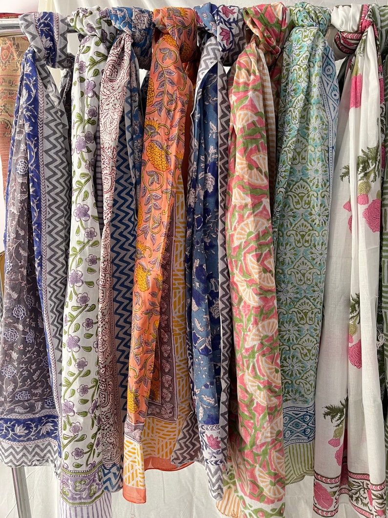May include: A collection of seven colorful scarves with various floral and geometric patterns. The scarves are made of cotton and are perfect for adding a touch of color and style to any outfit.