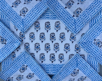 Op de afbeelding: Set van zes blauwe en witte katoenen servetten met een bloemenprint. De servetten hebben een zigzag-patroonrand.