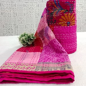 May include: A pink and purple kantha quilt with floral and geometric patterns. The quilt is made from recycled saris and is hand-stitched.