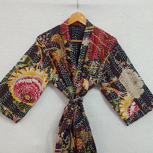 Może przedstawiać: Czarna bawełniana szlafrok z kwiatowym nadrukiem w odcieniach różowego, żółtego i czerwonego. Szlafrok ma pasek do wiązania i długie rękawy.