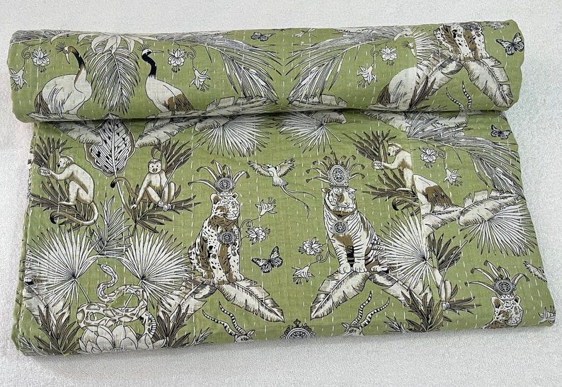 May include: Green kantha quilt with a white and brown pattern of animals, birds, and plants. The quilt is made of cotton and has a hand-stitched design.