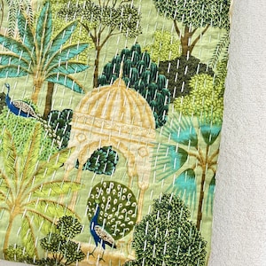 May include: A green and white kantha quilt with a peacock and a decorative archway design. The quilt features intricate stitching and a traditional Indian pattern.