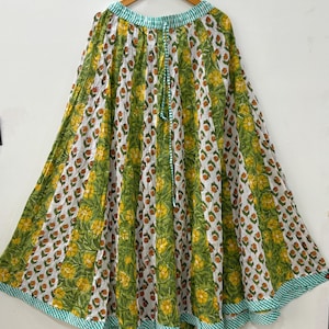 May include: A white, green, and yellow floral print maxi skirt with a green and white gingham trim. The skirt has a drawstring waist and is made of a lightweight fabric.
