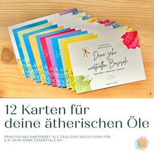 Könnte beinhalten: Ein Set aus zwölf farbenfrohen Karten mit Text und Aquarelldesigns, angeordnet auf einer Holzoberfläche. Die Karten zeigen verschiedene Farben, darunter Blau, Gelb, Rosa und Grün, mit botanischen Illustrationen und handgeschriebenem Text. Die Karten sind für ätherische Öle.