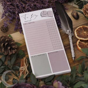 May include: A pink and green to-be-read list notepad with a book icon and the text "To Be Read". The notepad is divided into three sections: "This Month", "Next Month", and "In Future".