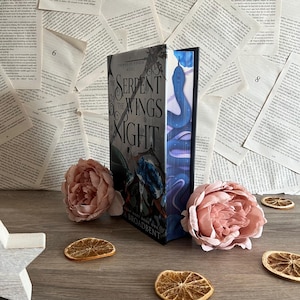 May include: A hardcover book titled "The Serpent & The Wings of Night" by S.A. Broadbent. The book cover features a dark blue and purple snake with a silver crown on its head. The book is part of the "A Crown of  Ixala" series.