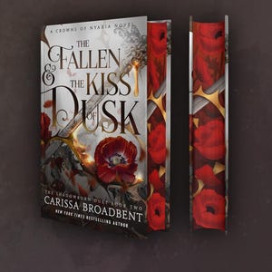 May include: A book cover for "The Fallen and the Kiss of Dusk" by Carissa Broadbent. The cover features a dark background with the title in elegant gold lettering. Red poppy illustrations and a decorative spine are also visible.