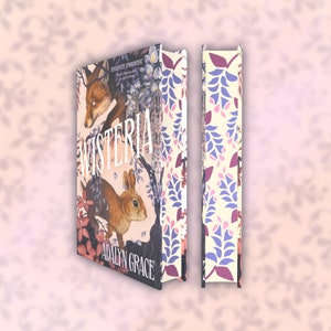 May include: A hardcover book titled "Wisteria" by Adalyn Grace, featuring a fox and a rabbit illustration. The spine displays a floral pattern in purple, pink, and cream. The cover art has a whimsical, illustrated style.