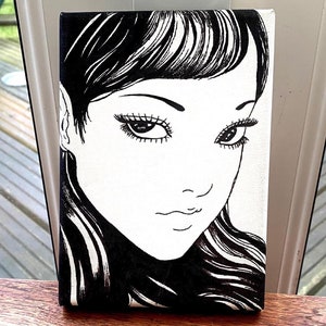 May include: Black and white illustration of a woman's face with long, flowing hair. The woman has large, expressive eyes and a delicate, feminine expression.