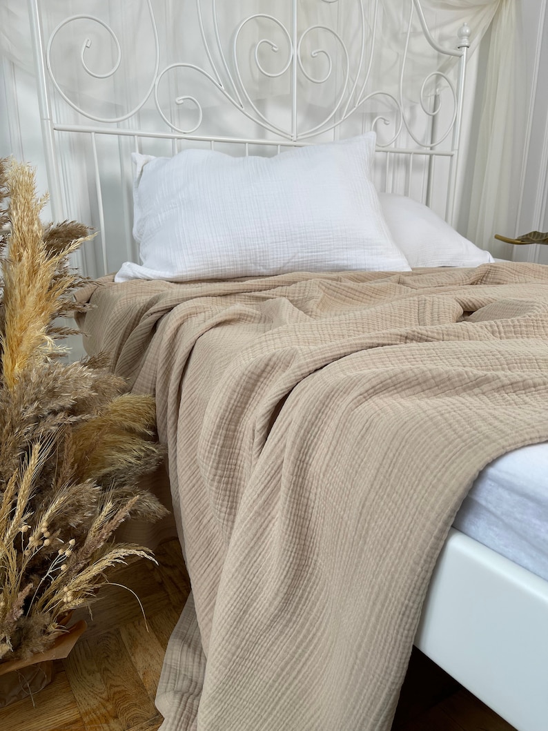 Pu&ograve; includere: Una coperta beige a nido d'ape &egrave; drappeggiata su un letto bianco con un cuscino bianco. La coperta &egrave; realizzata in tessuto morbido e traspirante, perfetta per aggiungere un tocco di calore e stile a qualsiasi camera da letto.
