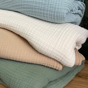 Pu&ograve; includere: Quattro quadrati di tessuto piegati in diversi colori: azzurro, bianco, beige e verde. Il tessuto ha una trama a nido d'ape.
