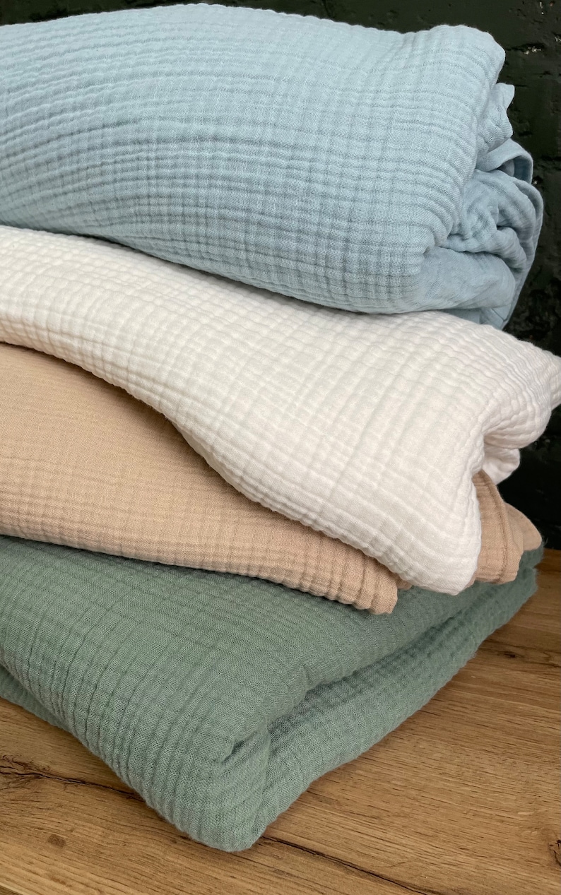 Pu&ograve; includere: Quattro quadrati di tessuto piegati in diversi colori: azzurro, bianco, beige e verde. Il tessuto ha una trama a nido d'ape.