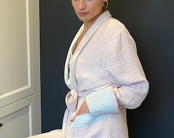 May include: A pink waffle-weave robe with a light blue trim and a matching pair of pants. The robe has a shawl collar, a tie belt, and pockets.