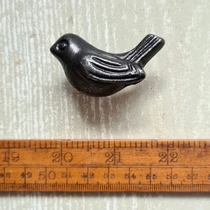 May include: A black metal bird-shaped cabinet knob or drawer pull. The bird is facing right and has a detailed design. The knob is approximately 5 cm long.