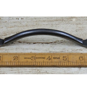 May include: A black metal cabinet pull with rounded ends. The pull is approximately 4 inches long.