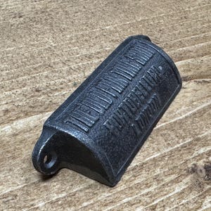 Peut inclure: Un ouvre-bouteille en métal coulé gris foncé en forme de cabine téléphonique londonienne. Les mots "Telephone London" sont en relief sur le côté. Il a un petit trou pour l'accrocher.