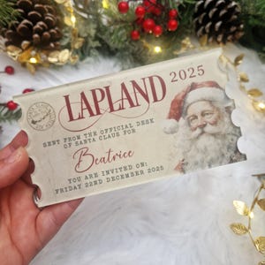 Peut inclure: Un billet de Lapland de style vintage pour 2025, avec le Père Noël et le texte "Envoyé du bureau officiel du Père Noël pour Béatrice". Le billet est de couleur crème avec du texte rouge.