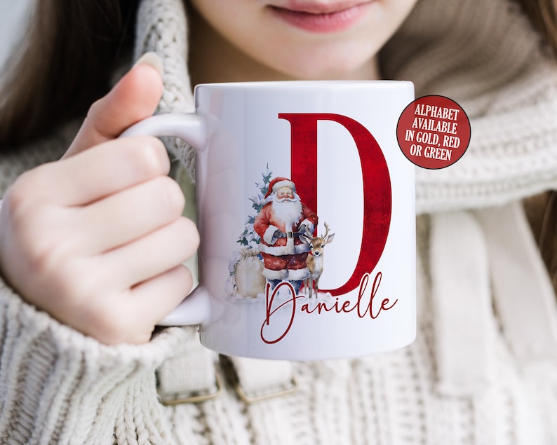 May include: White ceramic mug with a red letter D, a Santa Claus illustration, and the name Danielle. The letter D is available in gold, red, or green.