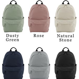 Puede incluir: Se muestran seis mochilas en varios colores: verde polvoriento, rosa, piedra natural, azul marino, gris puro y negro. Cada mochila tiene un asa superior, bolsillos laterales y un bolsillo frontal. El texto "BACKPACK COLOURS" est&aacute; en la parte superior.