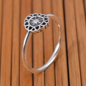 May include: A silver ring with a decorative, circular design featuring a star in the centre.