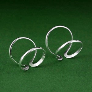 Puede incluir: Dos anillos de plata con un diseño retorcido. Los anillos son simples y elegantes.