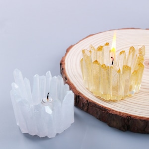 May include: Two crystal candle holders, one white and one gold, with a tea light candle in each. The candle holders are shaped like clusters of crystals.