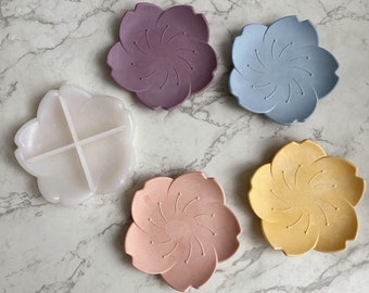 May include: Five silicone flower-shaped dishes in various colors, including purple, blue, pink, and yellow. One dish is divided into four sections.