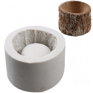 May include: A white silicone mold shaped like a tree stump. The mold has a round, hollow center for making candles or soap.